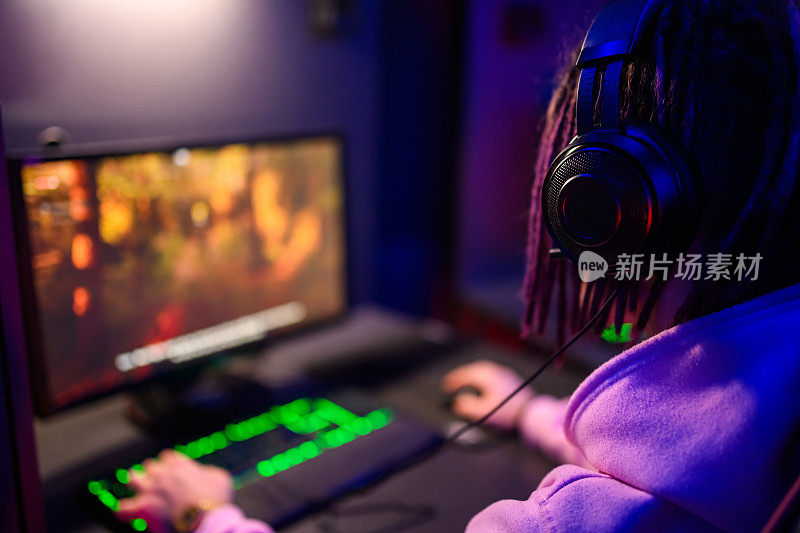 一个电子竞技玩家戴着耳机玩在线视频游戏的后视图