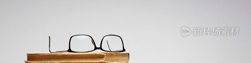 眼镜放在一本旧书上。特写镜头。有选择性的重点。