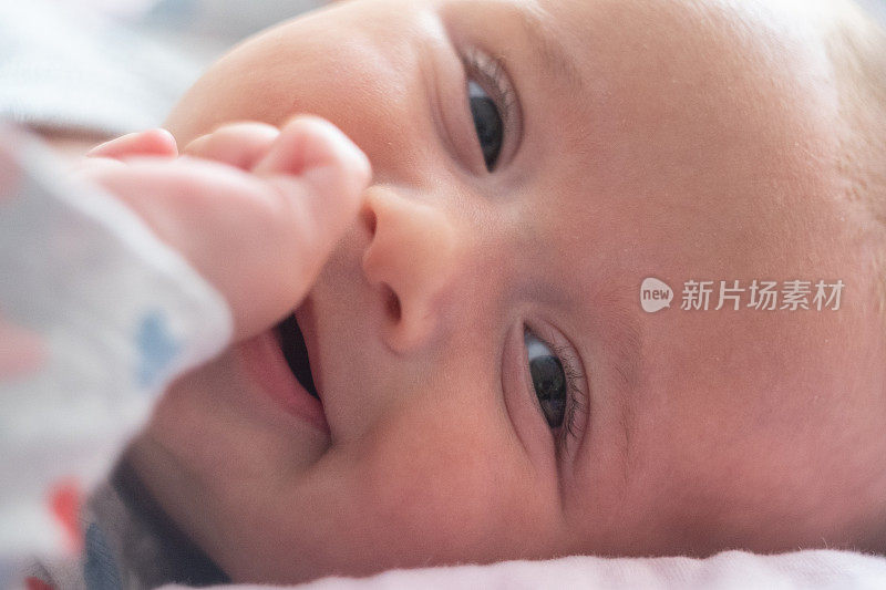 宝宝笑着看着镜头，带着爱。三个月的小女孩玩着笑着。COVID-19大流行期间的新生儿。