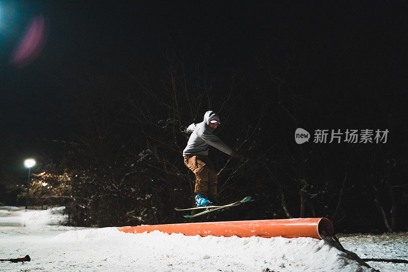 自由式滑雪者晚上在城市公园的轨道上跳跃