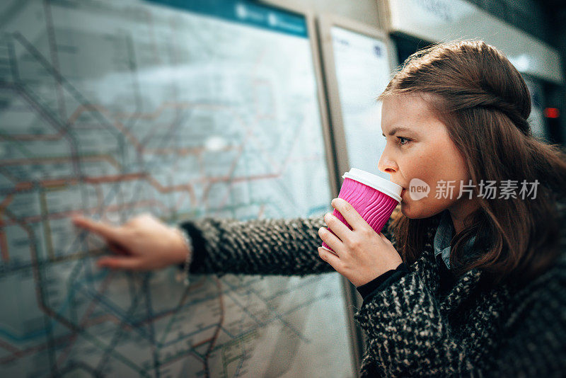 年轻的成年女子在车站肖像上读时刻表