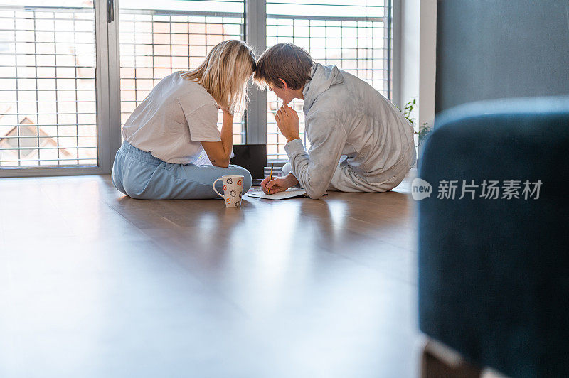 年轻夫妇在地板上用笔记本电脑