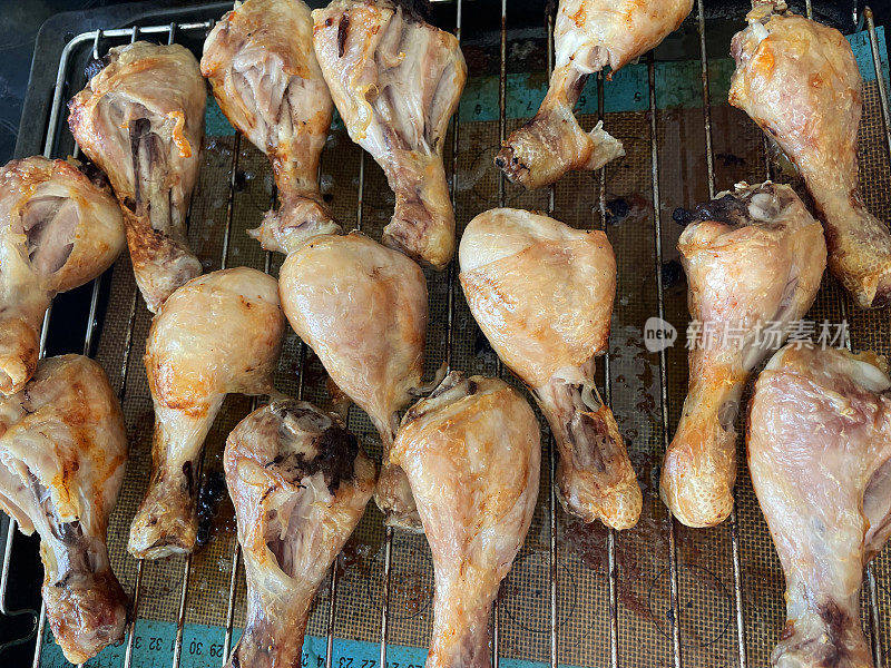 形象酥脆，金色的鸡腿腿放在烤架上，皮脂烹饪和滴在硅胶垫下面，俯瞰