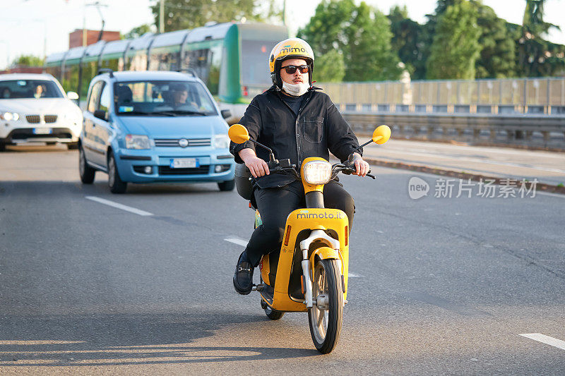 在繁忙的城市街道上骑摩托车的人。骑摩托车驾驶助力车。2020年5月26日，意大利米兰
