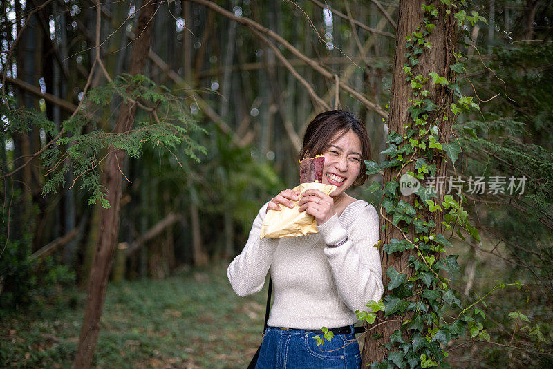 年轻女子在森林里吃烤红薯
