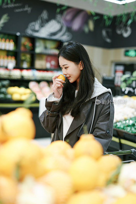 亚洲女孩在超市买橘子