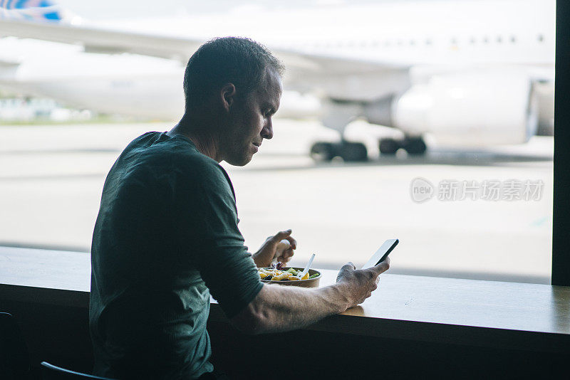 一名年轻人在机场用餐时查看手机