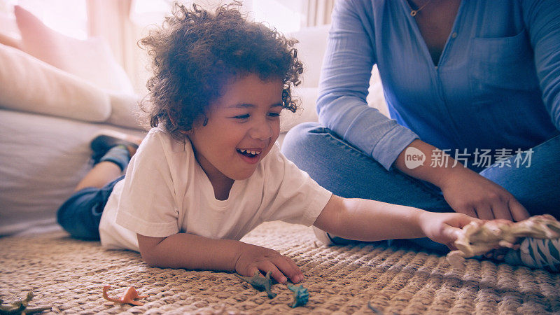 一个小男孩和他的妈妈在家里一起玩玩具恐龙