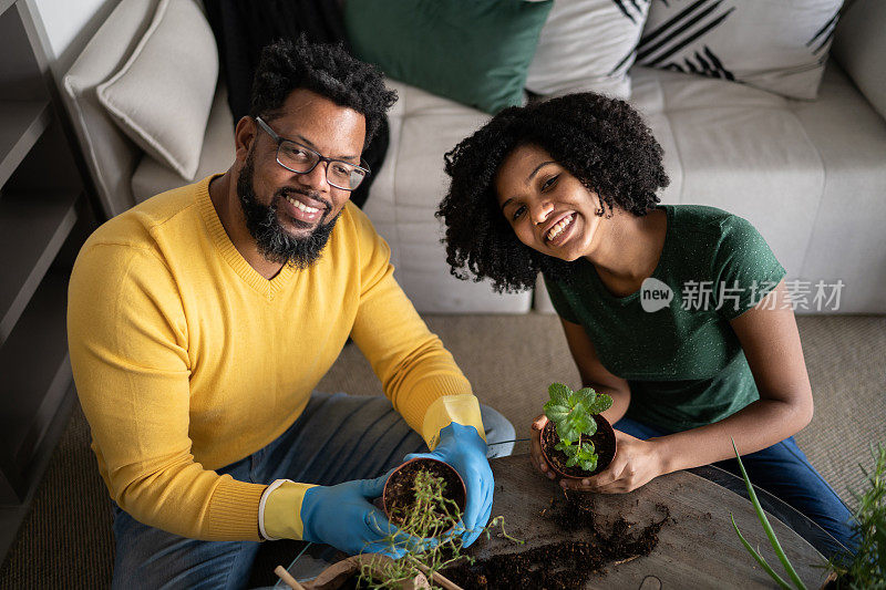 父亲和十几岁的女儿在家里照顾植物的肖像