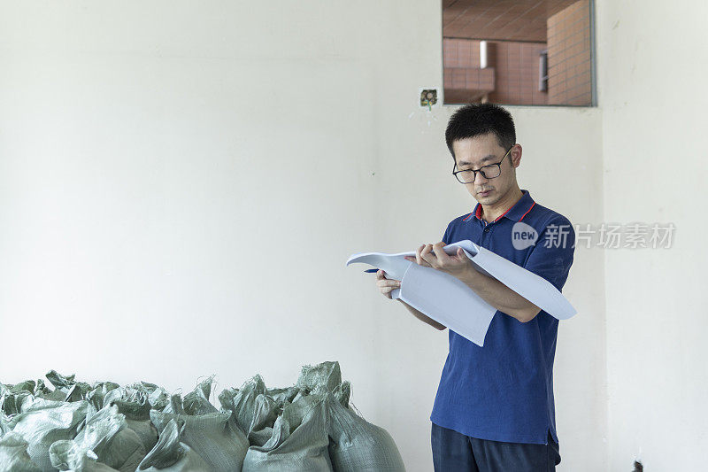 亚洲男性工程师在装修工地处理施工图纸