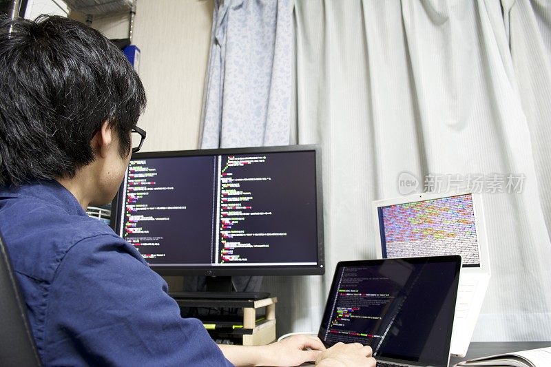 一个年轻的亚洲程序员在他的房间里编程