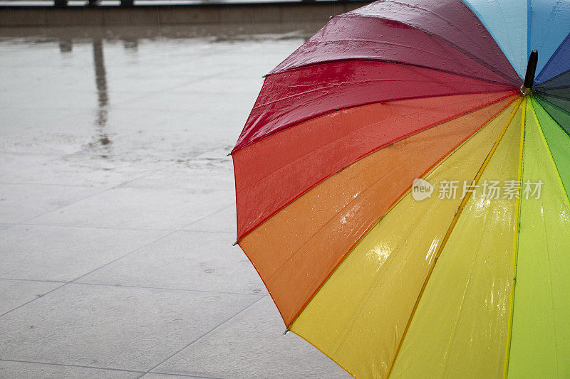 雨点落在彩虹伞上，天以自然为背景