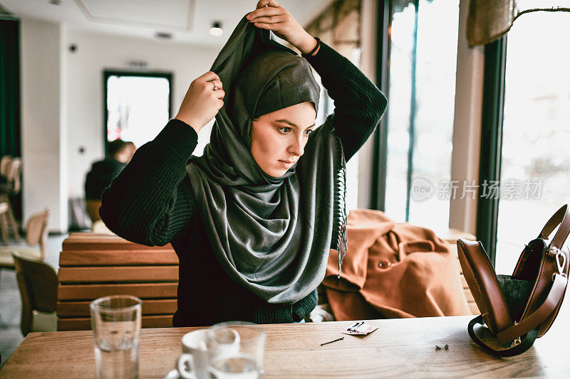 穆斯林女性在享受咖啡时戴上她的希贾布