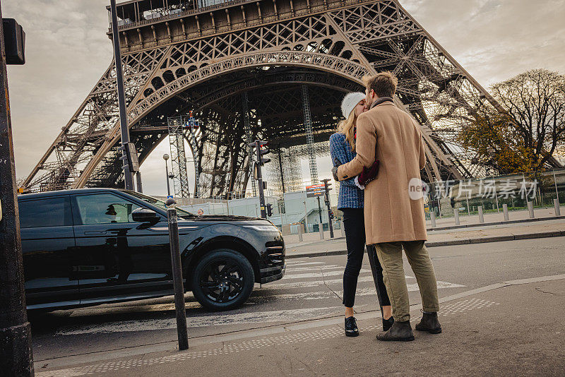 傍晚，一对浪漫的情侣在巴黎埃菲尔铁塔前拥抱亲吻