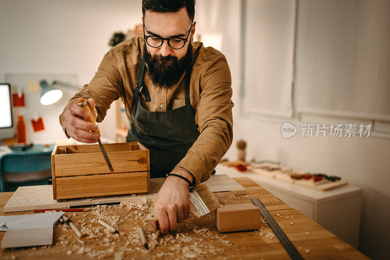 男艺术家在工作室的工作台上用手工工具和木箱