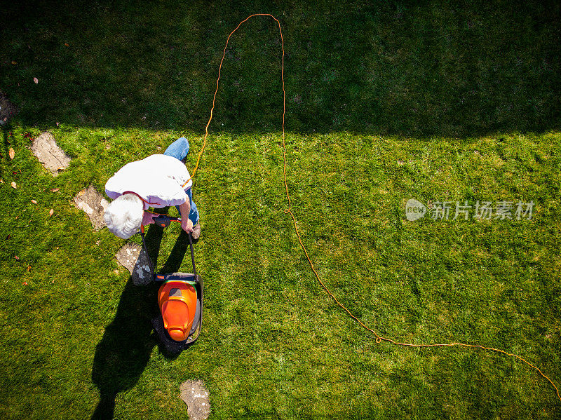 鸟瞰图中的人在花园里用割草机割草