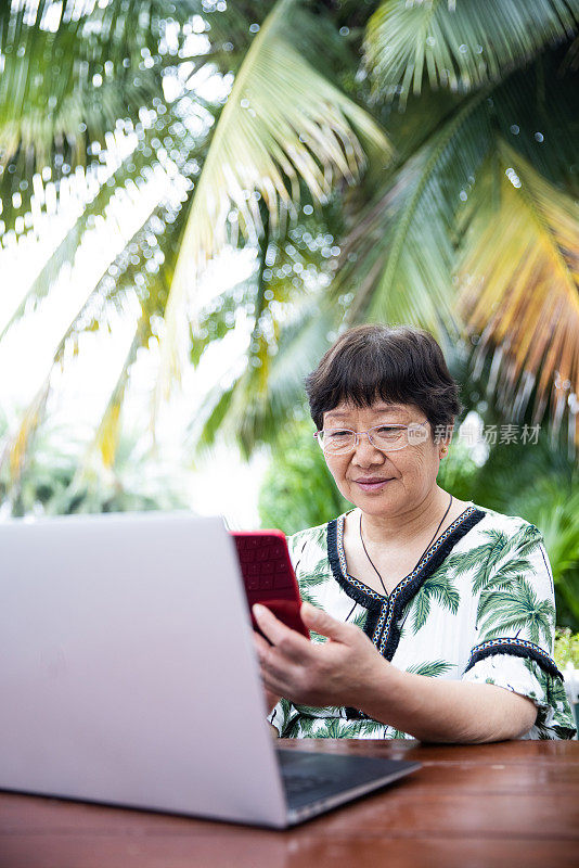 老年女性在户外使用笔记本电脑和手机