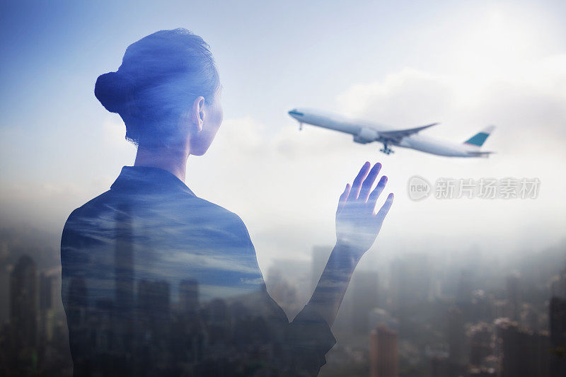 年轻的中国女子站在机场候机楼出发区窗口向飞机挥手