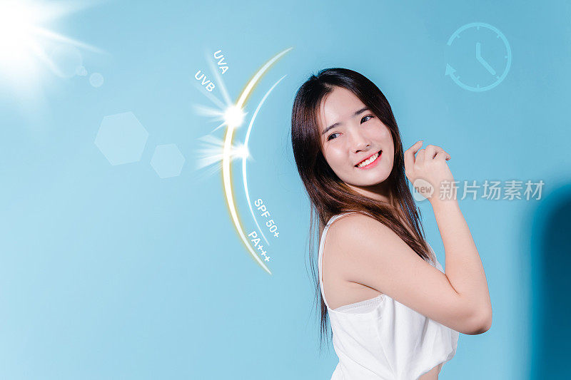 微笑的亚洲美女持有防晒霜与防晒紫外线或防晒霜，防晒霜在蓝色的背景