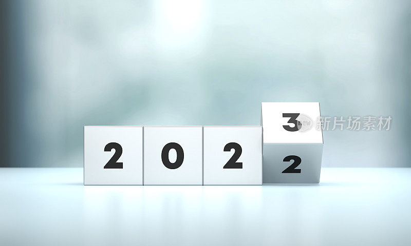 “2022”和“2023”书写块坐在蓝色表面前的散焦背景
