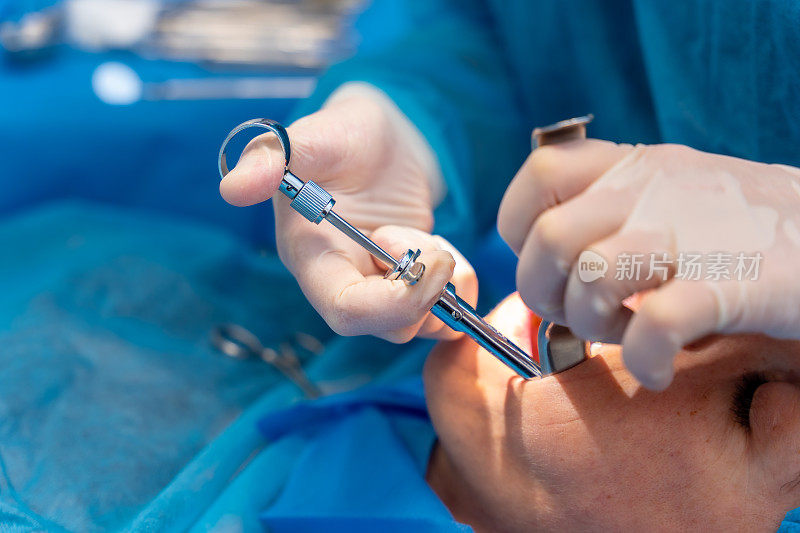 牙科诊所，牙科医生给病人的口腔下部注射麻醉剂