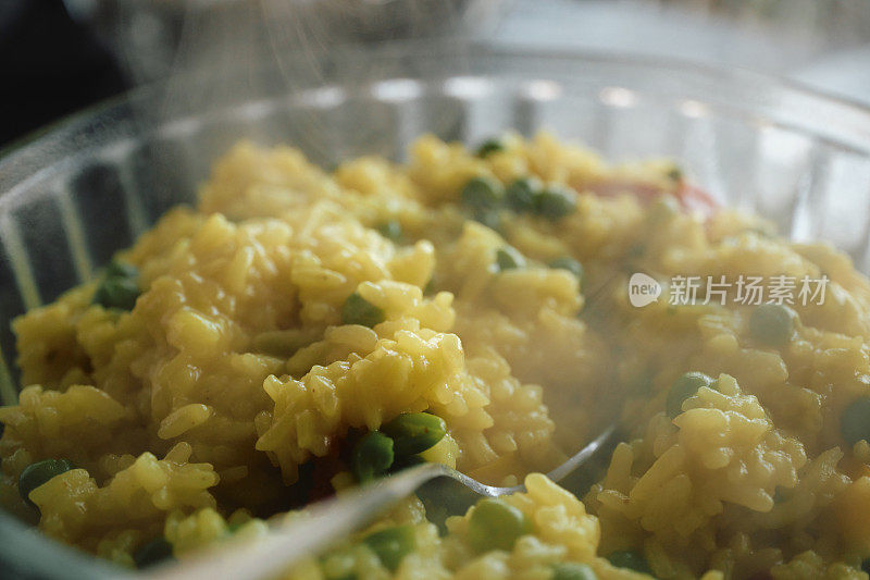 特写一碗用姜黄和豌豆煮的热气腾腾的米饭。