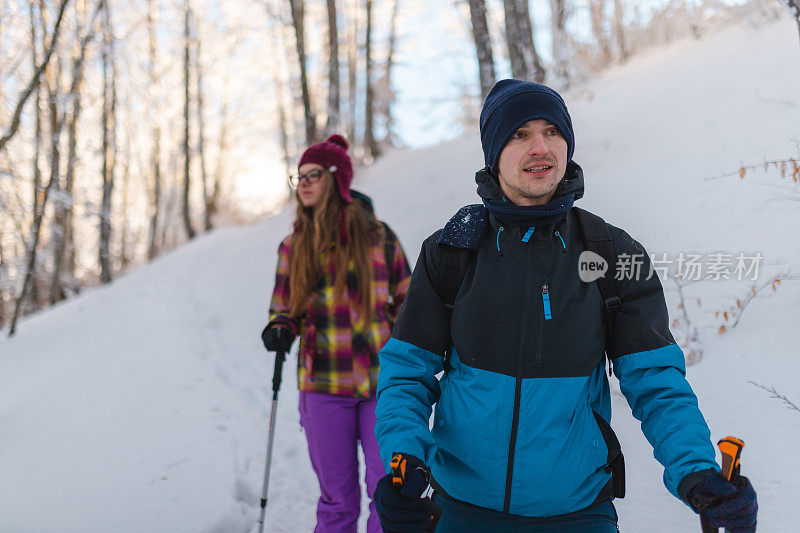 年轻的男性徒步旅行者和他的女性朋友一起从雪山小径上爬下来