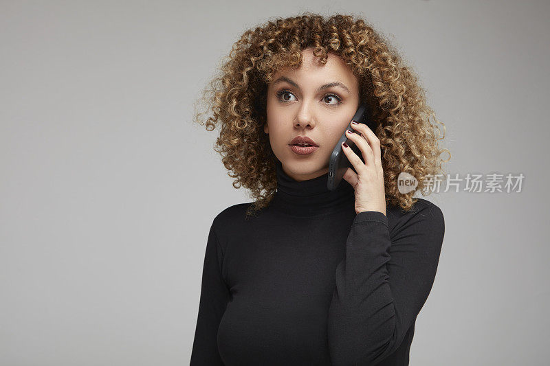 一头卷发的年轻女子焦急地与人交谈。