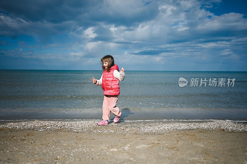 小女孩在海滩上跑步，对着美丽的海景。