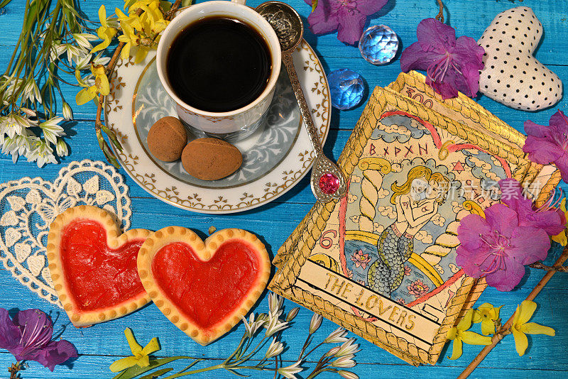 有爱情象征的塔罗牌，女巫仪式桌上的旧杯子和饼干。神秘，深奥和占卜静物。神秘的背景与复古的物品
