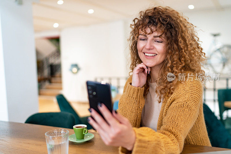 漂亮的年轻女子在咖啡店使用智能手机