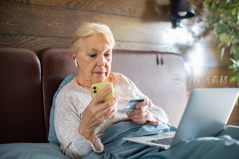 老女人在卧室用笔记本电脑网购