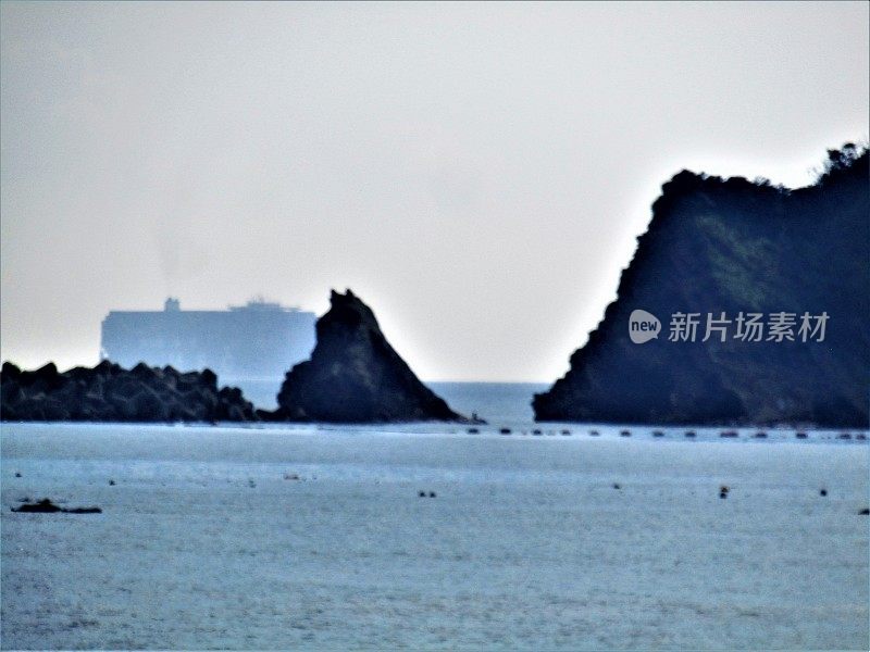 日本。海景与岩石岛屿和巨大的海上船只在地平线上。