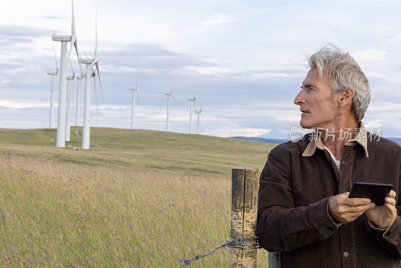 高级能源技术人员望向风力涡轮机，望向远处的群山