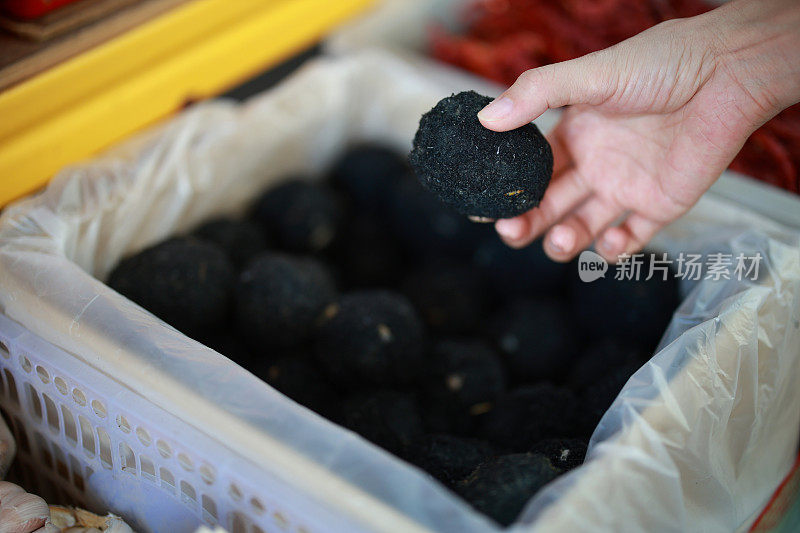 一名亚洲妇女在市场摊位上仔细挑选中国咸蛋的特写镜头。