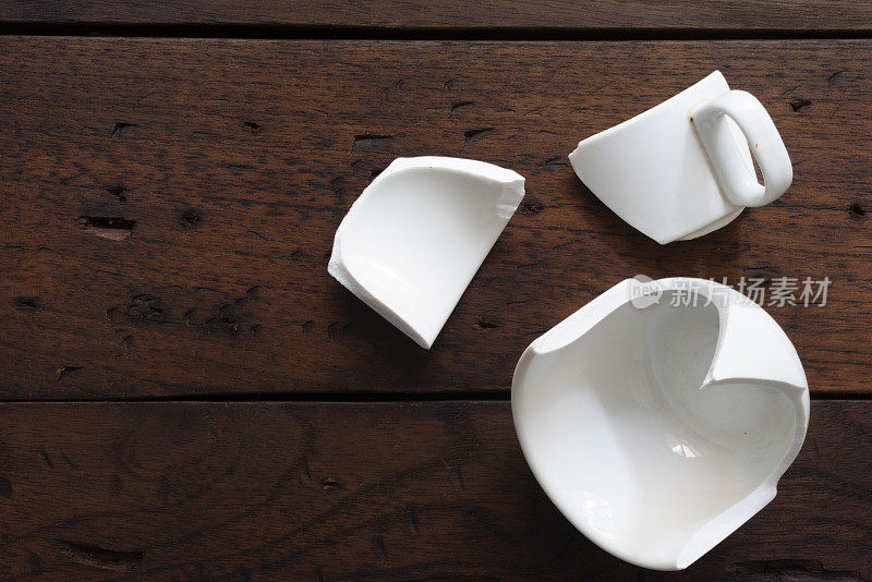 木桌上破碎的白色杯子