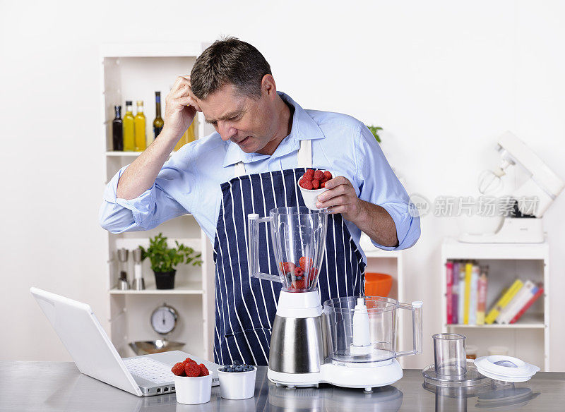 一个成熟的男人一边用笔记本电脑做饭一边思考