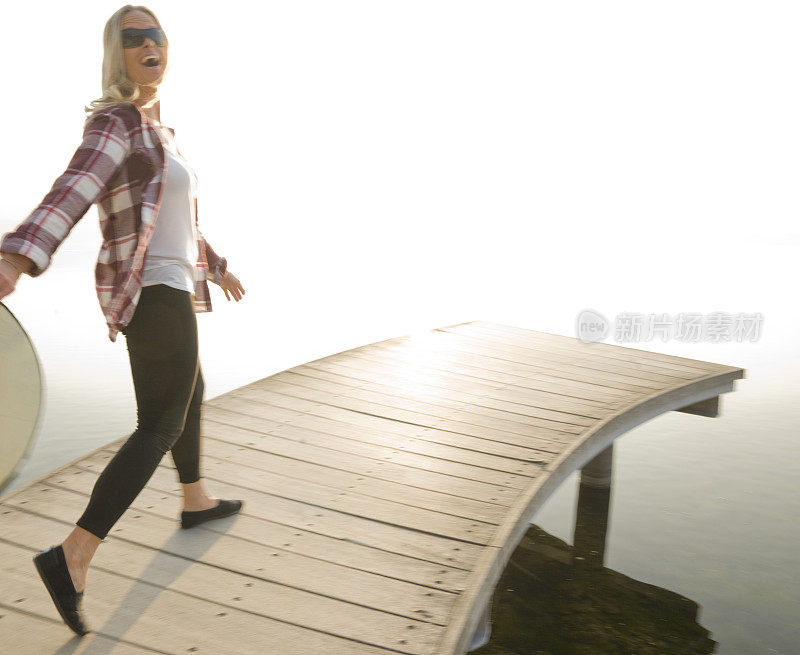 女人走在湖边的木码头上