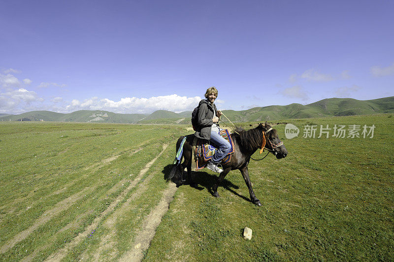 在中国四川省大公附近骑马的西方游客