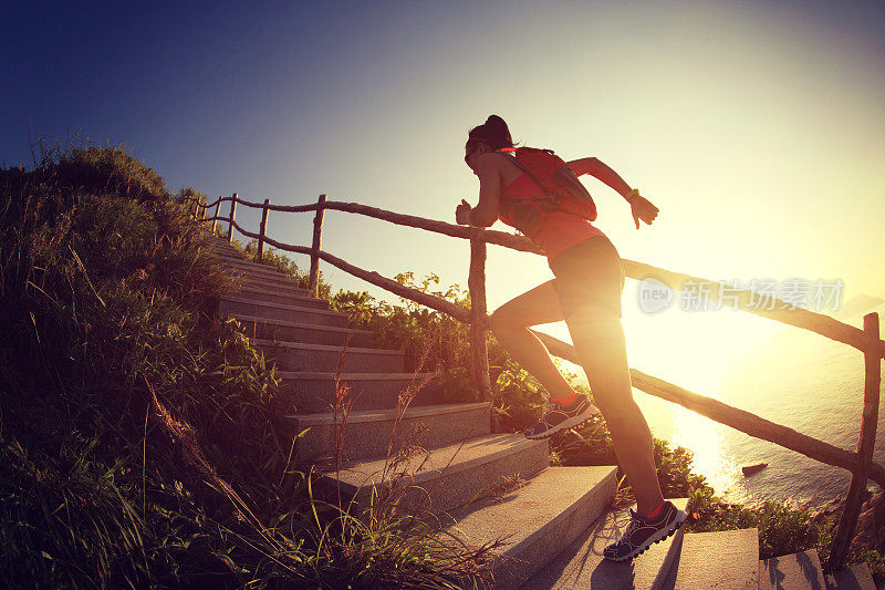 健身女跑步者在海边的山楼梯上跑步，