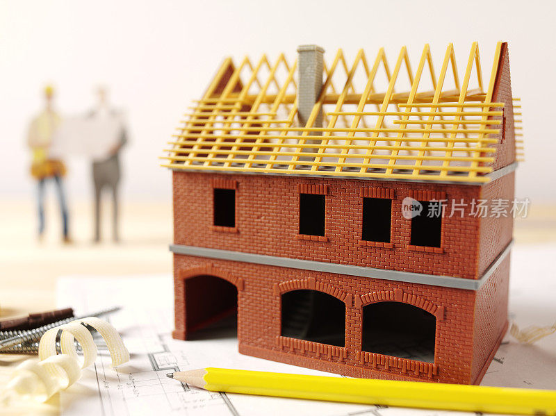 建造者和测量师与一个玩具房子模型