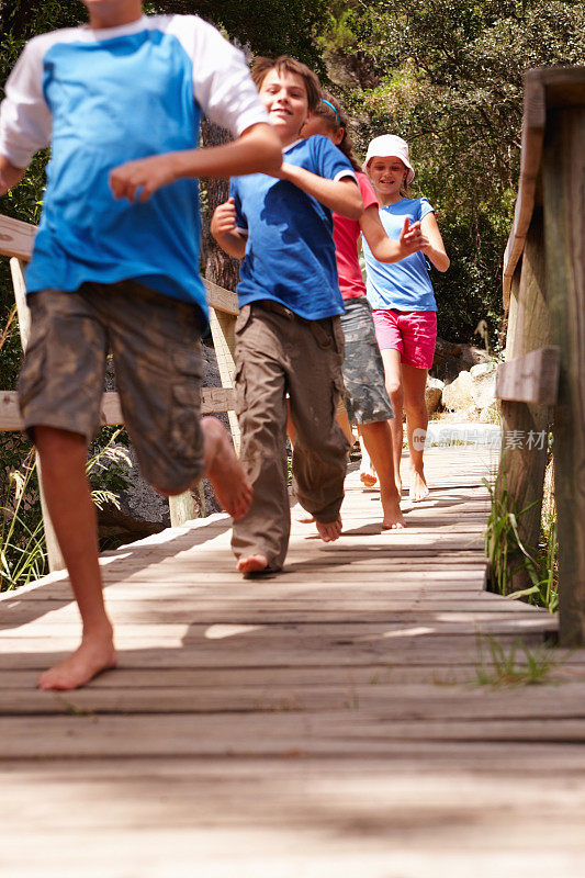 一群快乐的孩子在户外的木桥上奔跑
