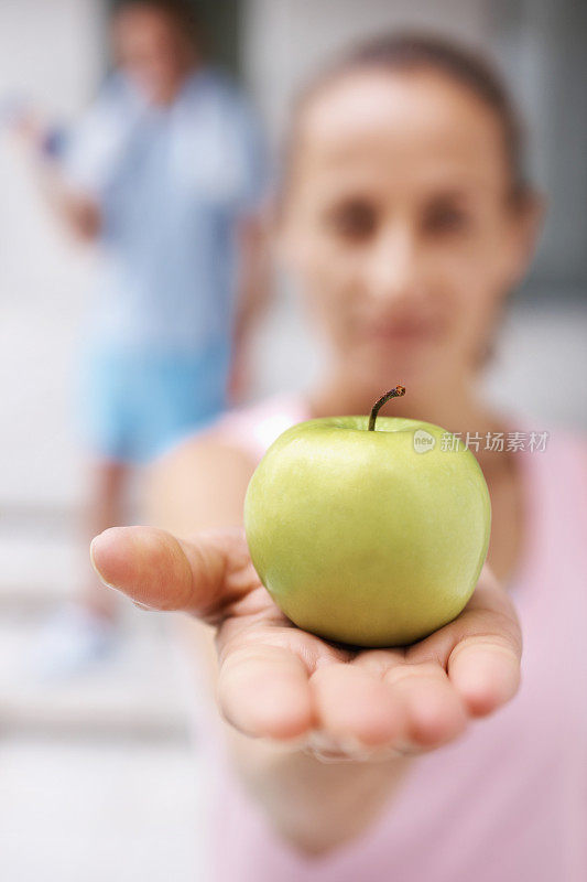 模糊的女性特写给你一个绿苹果