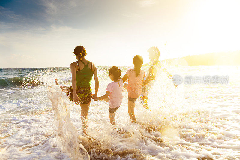 快乐的年轻家庭在海滩上玩日落