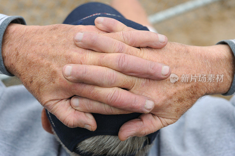 一个人坐在那里，双手交叉放在头上