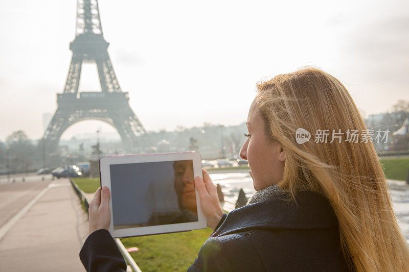 一名年轻女子在巴黎用数码平板电脑拍照