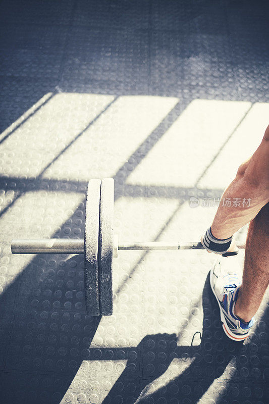 年轻男子在健身房举杠铃的裁剪图像