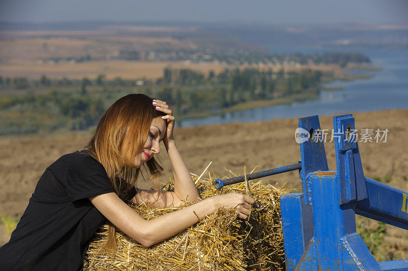 一个年轻女孩倚着一堆稻草