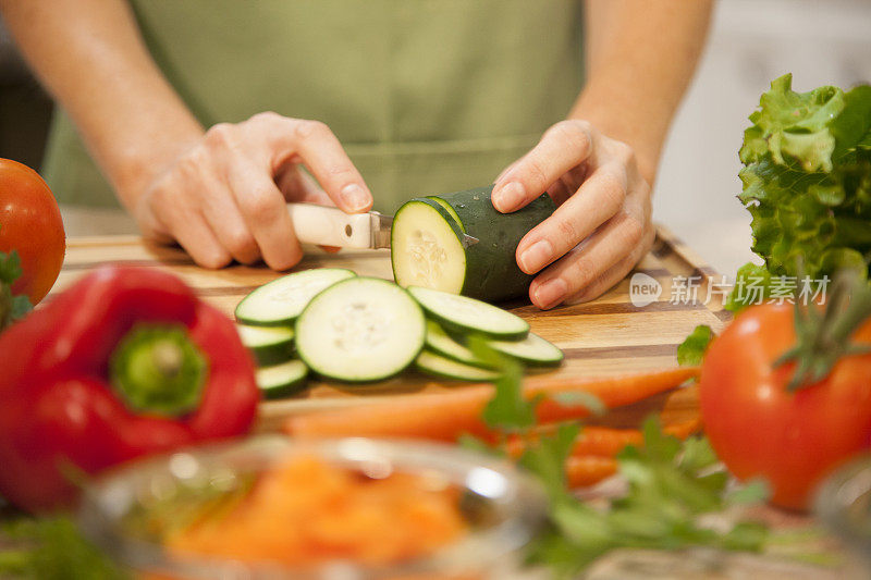 女人在家庭厨房里切黄瓜，蔬菜。沙拉。
