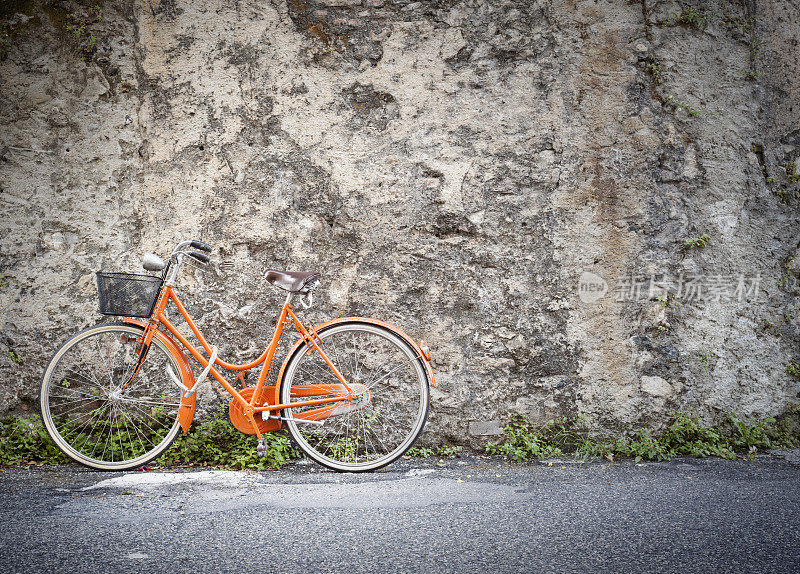 靠在旧墙上的橙色自行车